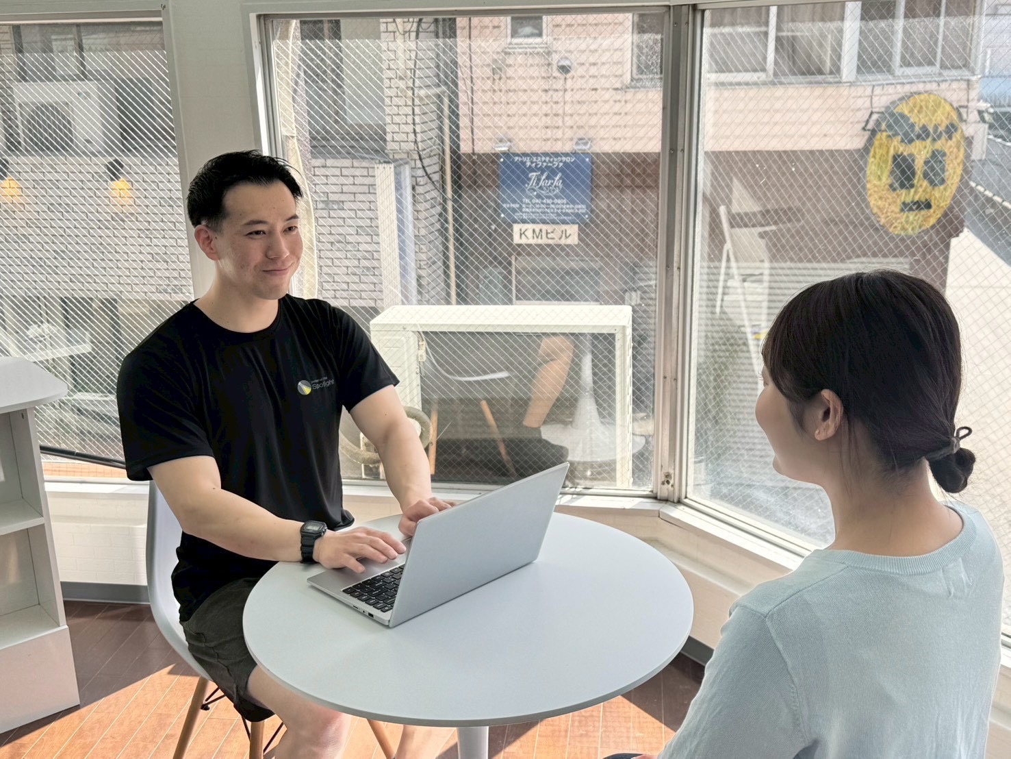 窓際のテーブルでお客様のお話を伺うトレーナー